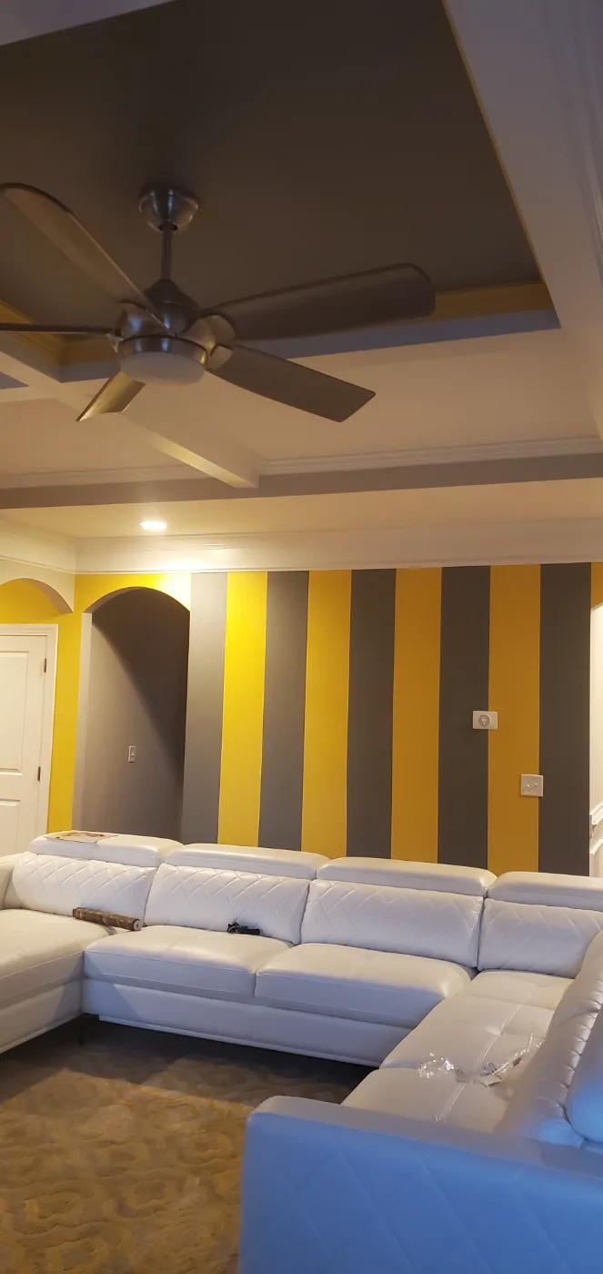 Living room with a gray and yellow striped accent wall and painted tray ceiling in Columbia SC