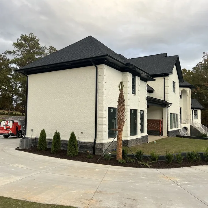 Completed custom home exterior in painted white brick with dark stone base near Columbia SC