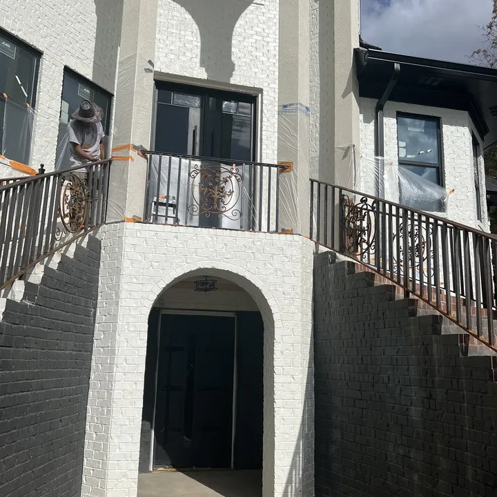 Painter working above a painted brick entry with an arched doorway on a Midlands custom home