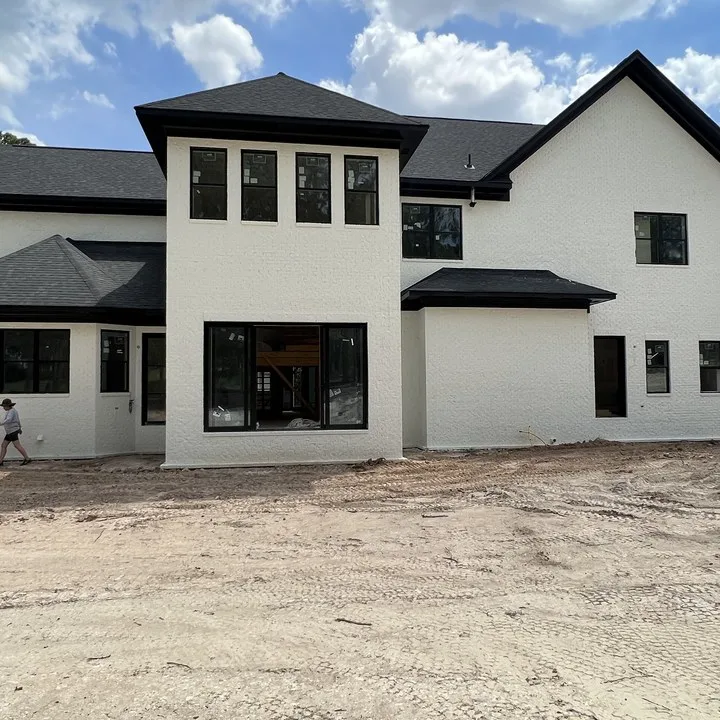 Rear elevation of a painted white brick home with black windows near Columbia SC