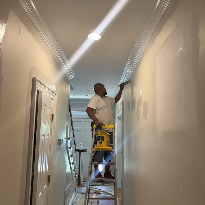 TAP painter cutting in crown molding along a hallway ceiling in a Columbia SC home