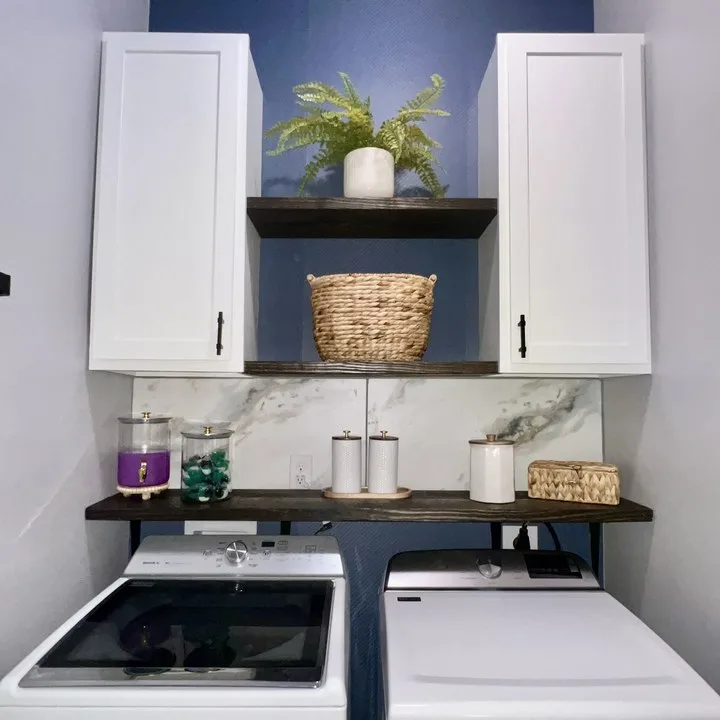 Laundry room with navy accent wall, white cabinets, and painted shelving in Columbia SC